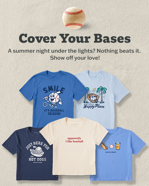 Assortment of Life is Good baseball tees in blue, light blue, navy, cream, and sky blue, featuring "Smile It's Baseball Season," "Happy Place," "Just Here for the Hot Dogs," "Apparently I Like Baseball," and ballpark snack graphics. Header reads "Cover Your Bases."