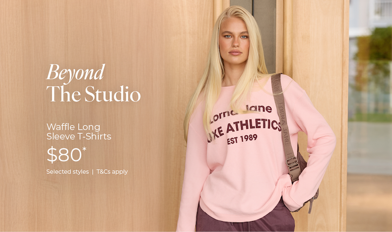Model wearing pink Lorna Jane Waffle Long Sleeve T-Shirt, $80*, leaning against timber wall.