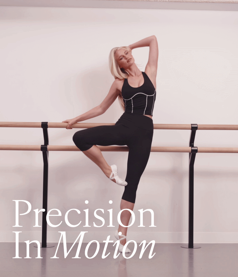 Precision In Motion. Woman in a black crop and cropped leggings at a ballet barre.