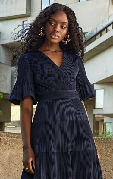 PLEATED PUFF SLEEVE DRESS  Effortlessly elegant. The flowing trapeze shape, puffed sleeves, and wrap-style bodice, flatters while pleats add movement.