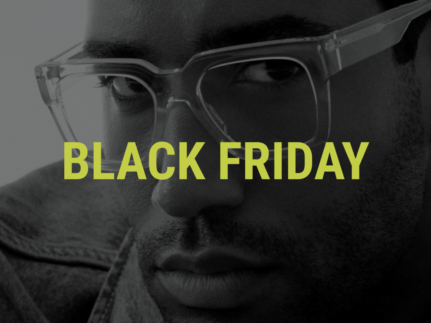 Schwarz-weiß-Aufnahme eines Mannes mit eckiger, transparenter Brille, der direkt in die Kamera blickt. Darüber der Schriftzug " Black Friday" in Neuongelb