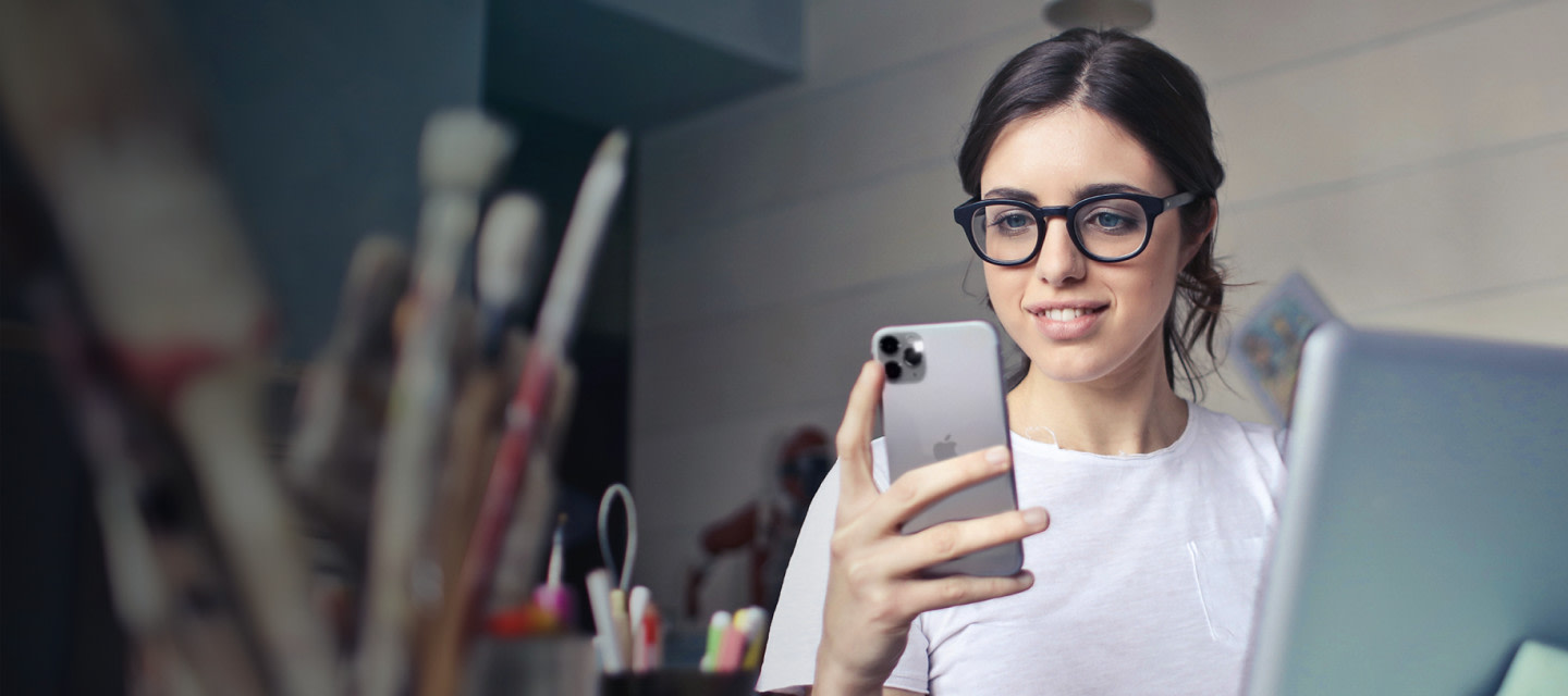 Bild einer Frau, welche eine Brille mit Kunststoffrahmen trägt. Sie schaut begeistert auf ihren Bildschirm