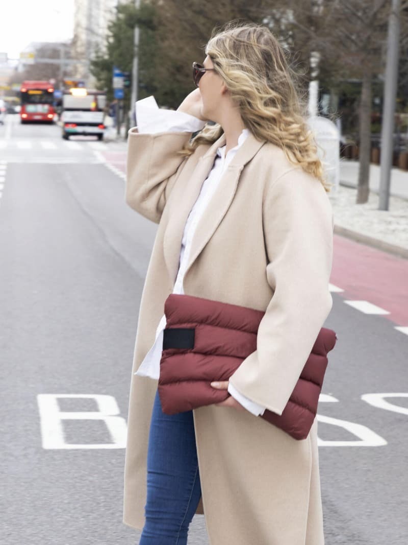 dame med kåpe og jeans som bærer en pc-veske i dun