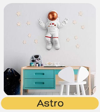 Child's bedroom with astronaut wall sculpture and star decals above teal drawer unit and white chair, toys on desk