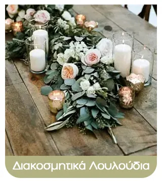 Decorative floral table centrepiece with pink and white roses, eucalyptus foliage and assorted candles in glass holders on a rustic wooden table