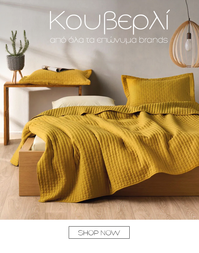 Mustard-yellow quilted bedspread and matching pillows on a low wooden platform bed with bedside table, potted plant and pendant lamp