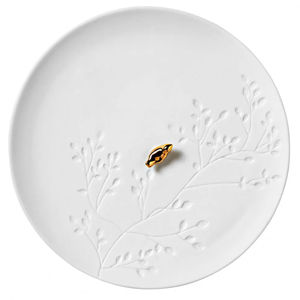 White ceramic round plate with embossed botanical twig pattern and small gold Saturn planet charm in centre