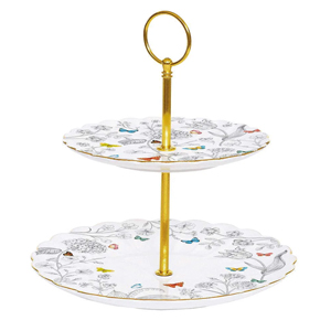 Two-tier white porcelain cake stand with colourful bird and floral pattern, gold metal centre rod and handle