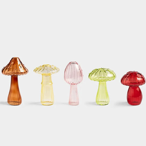 Five coloured glass mushroom sculptures in a row on white background (amber, yellow, pink, light green, red)