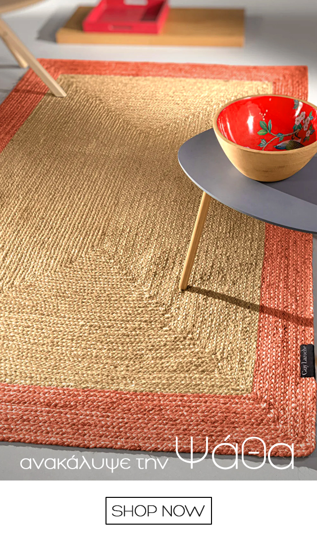 Handwoven natural jute rug with coral border beneath a small grey side table holding a red floral bowl, minimalist interior styling