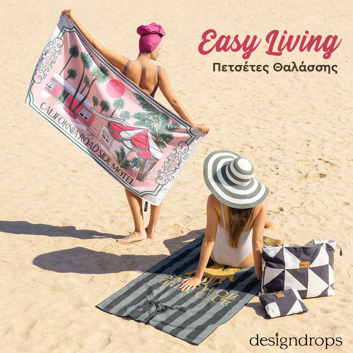 Two women on a sunny sandy beach with colourful printed beach towels, a striped sun hat and a beach bag nearby