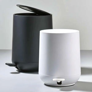 Pair of compact cylindrical pedal bins in white and black matte plastic with flip lids, minimalist bathroom or kitchen waste bins