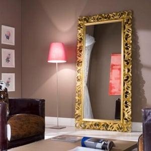 Ornate gold-framed full-length mirror leaning against wall in a stylish living room with a pink floor lamp and armchairs