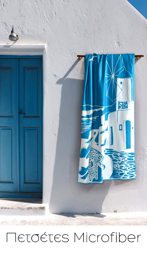 Blue microfibre towel with white Greek island design hanging on sunlit white wall beside a blue door