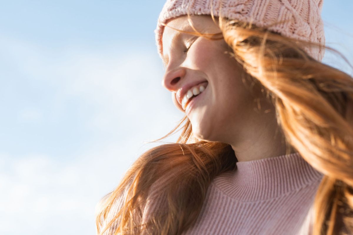 an image of a woman with long hair wearing a pink beanie and sweater made in Finland