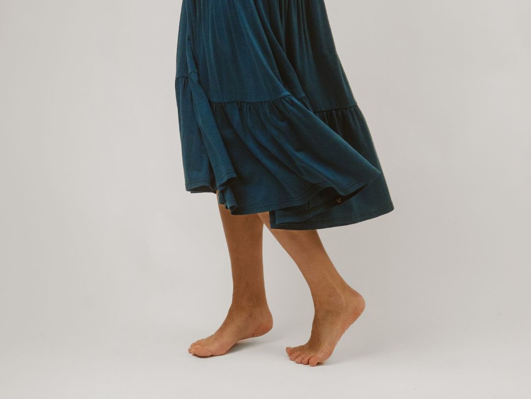 Lähikuva Lily merinomekon hulmuavasta helmasta naisen päällä. Väri sinivihreä.