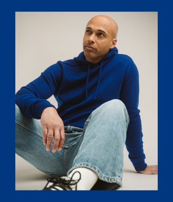 Syväsininsen Virta hupparin miehen päällä joka istuu lattialla.