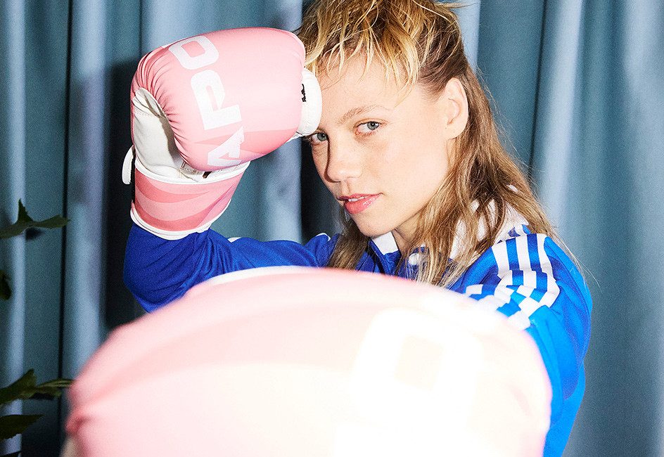 Person in blauer Sportbekleidung mit rosa Boxhandschuhen, die eine Boxhaltung einnimmt.