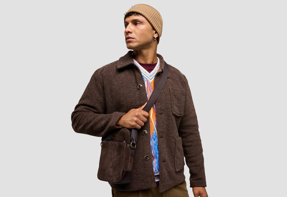 Mann mit Mütze und brauner Jacke und Tasche