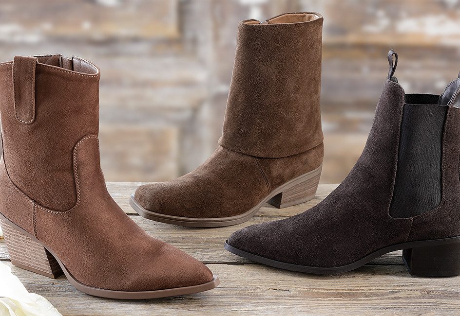 drei verschiedene Cowboy-Boots stehen auf einer Holzfläche