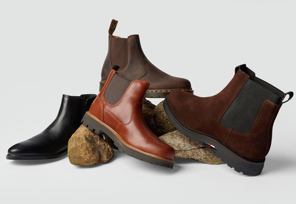 verschiedene Boots stehen wie achtlos hingestellt auf einem Haufen vor grauer Wand