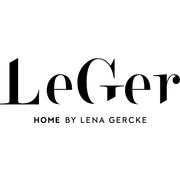 Frau sitzt entspannt auf einem weißen Bett im Schlafzimmer.