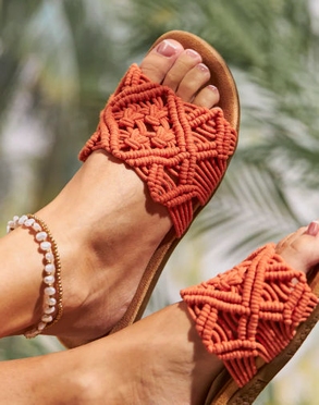 Füße mit Pantoletten mit modischem Häkelmuster in Orange