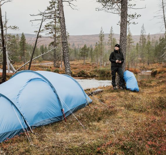 Kuvassa teltta ja henkilö metsässä