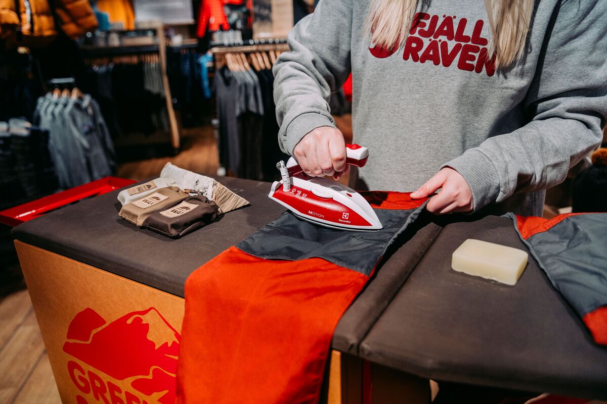 Nainen silittämässä vaellushousuja silitysraudalla.