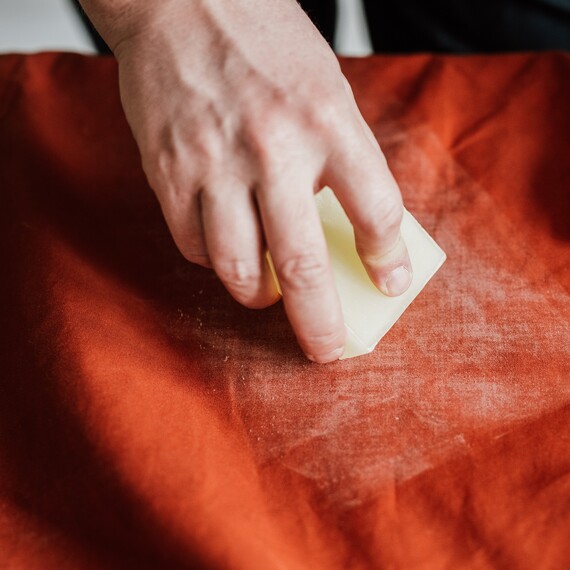 Käsi vahaamassa G-1000 materiaalista valmistettua vaatetta