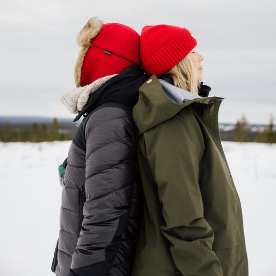 Kaksi ihmistä nojaamassa toisiinsa selät vastakkain.