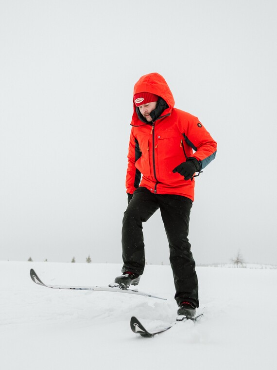 Mies suksien kanssa lumihangessa
