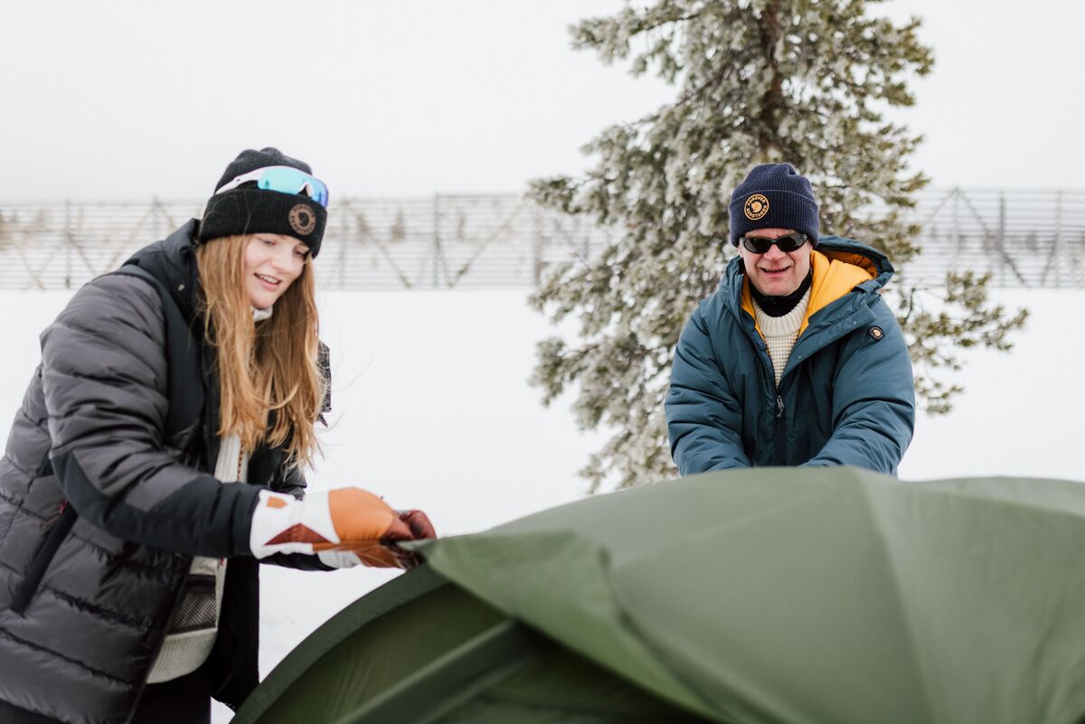 Nainen ja mies pystytt&auml;m&auml;ss&auml; telttaa talvimaisemassa