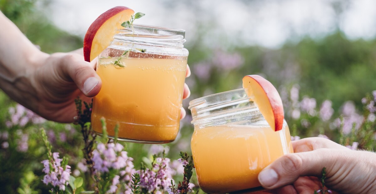 Kuvassa kaksi lasipurkkia t&auml;ynn&auml; retkibellini- juomaa skoolaa toisiaan kohti