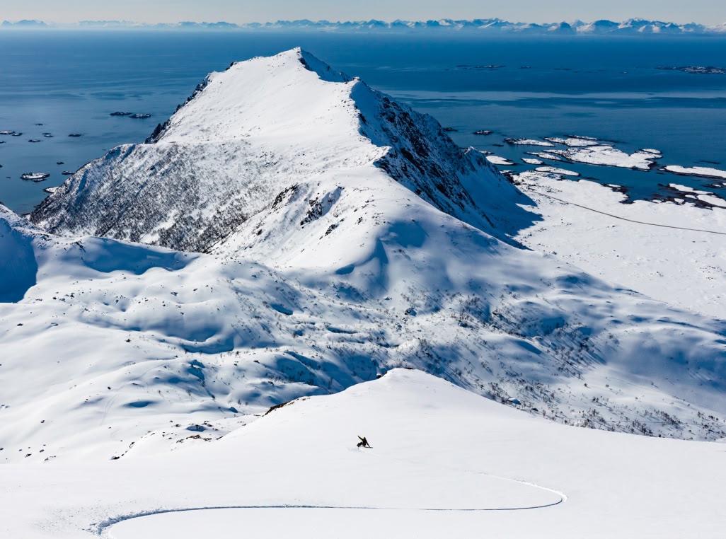 A snowboarder makes wide turns down the mountain.