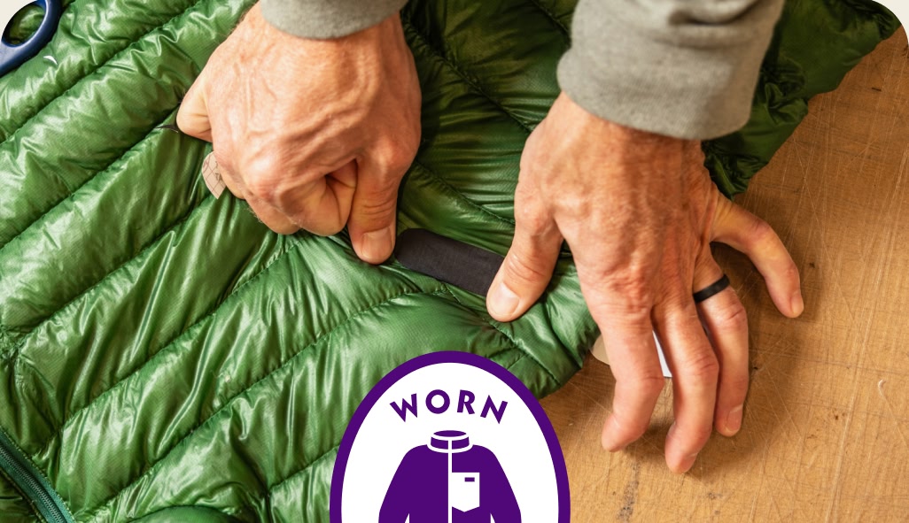 A person places a patch on a down jacket.