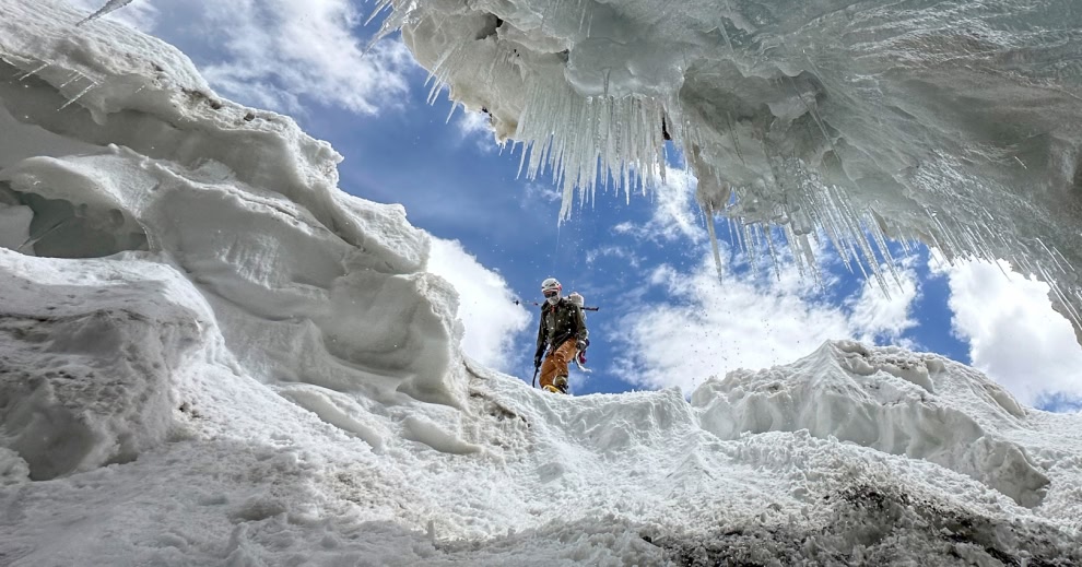 A mountaineer peers into a crevasse.
