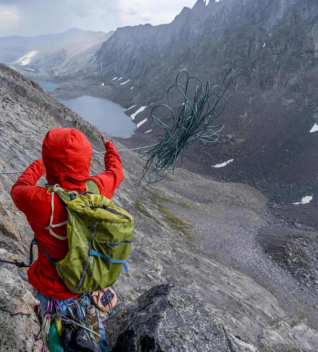 A climber throws a rope to rappel down a rock face.