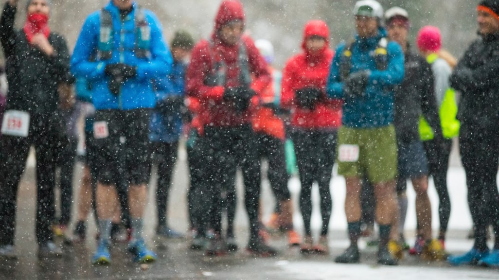 A group of runners standing in the rain about to start a race.