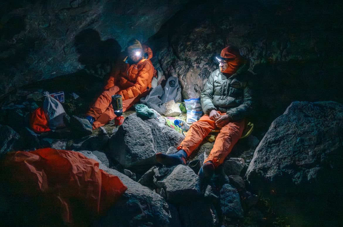 Two climbers chat while sitting on rocks at camp.