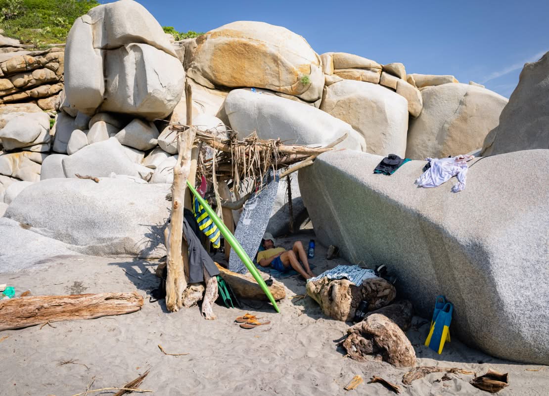 A surfer takes a nap on the beach.