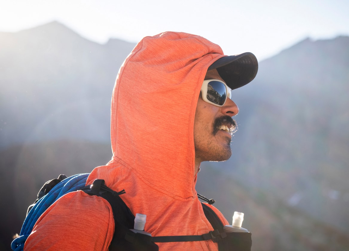 A trail runner wearing a hydration vest looks into the distance.