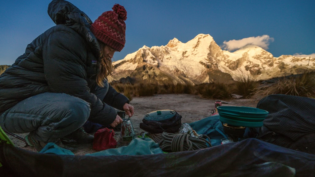 A person cooks a dehydrated meal at a campsite in the mountains.