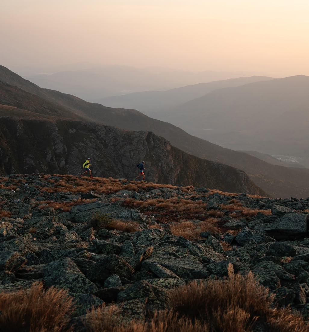 Patagonia. Men’s New Favorites. Two people running on a mountain at sunrise.