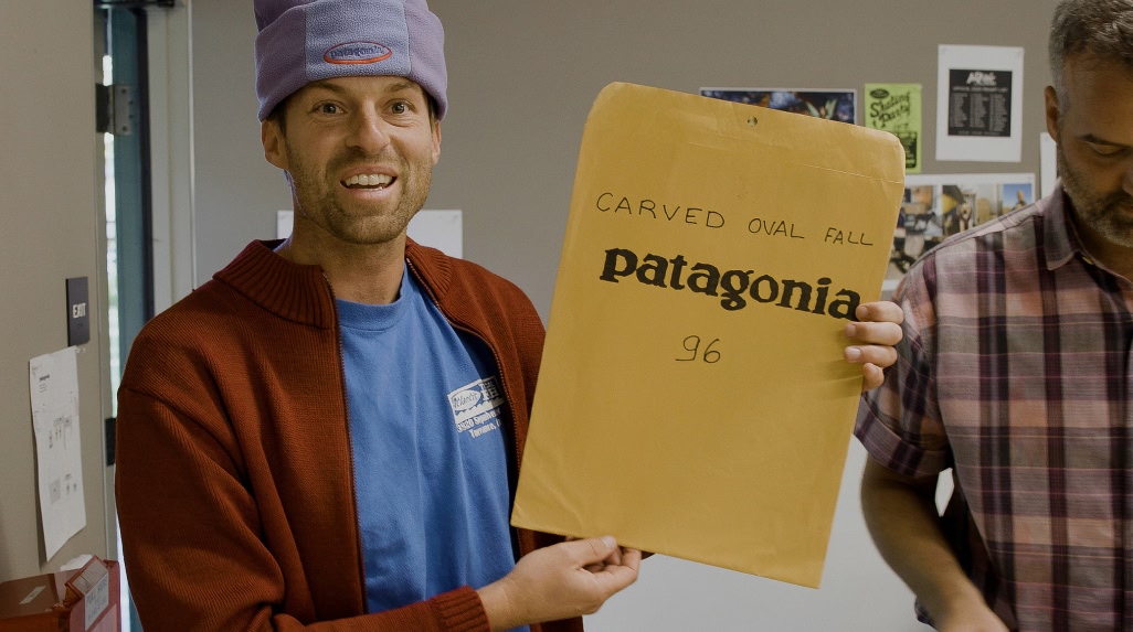 A designer holds up a manila envelope.