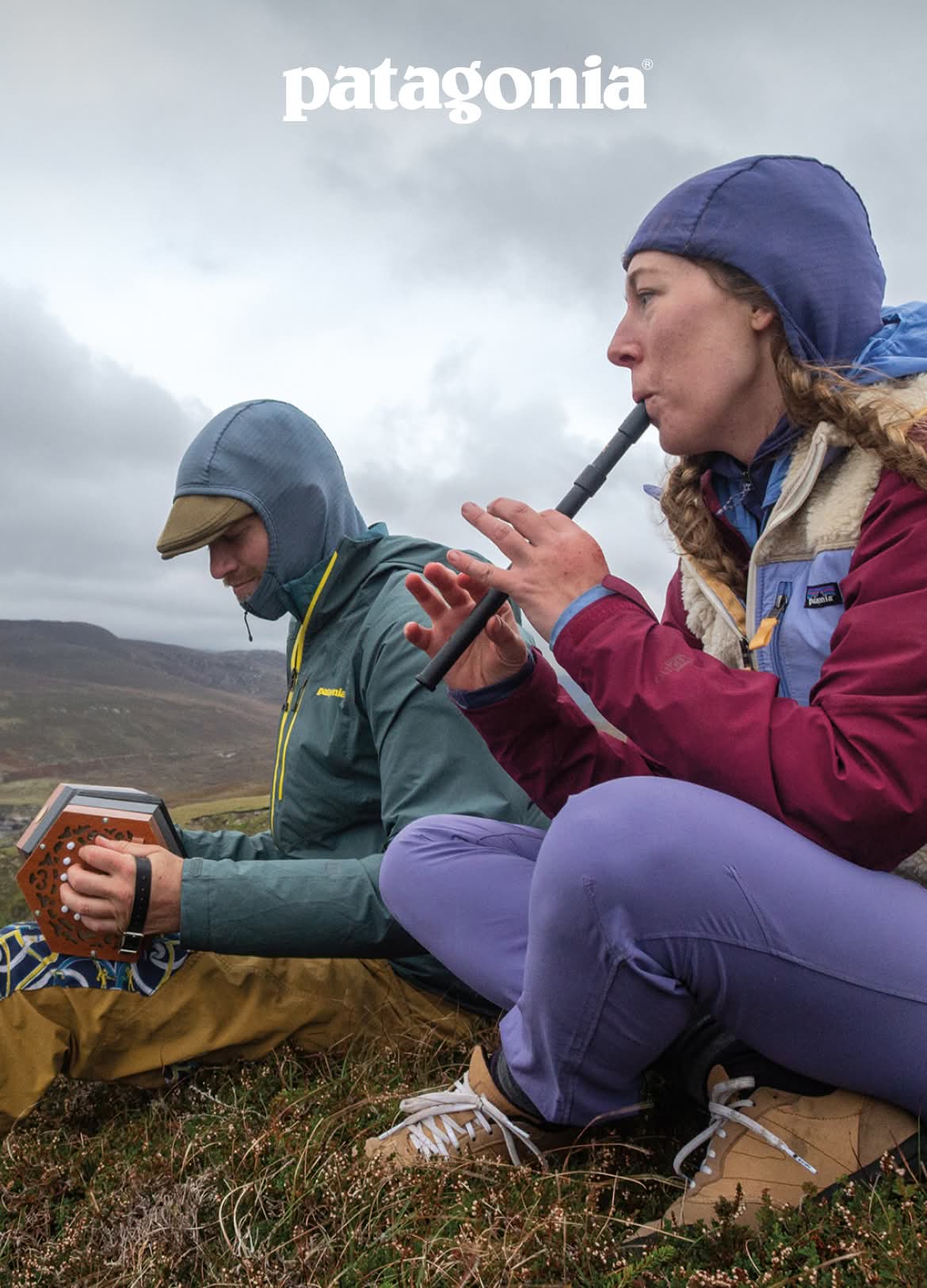 Patagonia.Two people play musical instruments while sitting on wild grass.