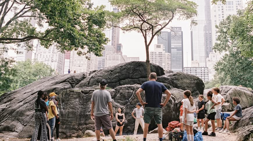 A group of youth activists and mentors stand in a circle in a city park.