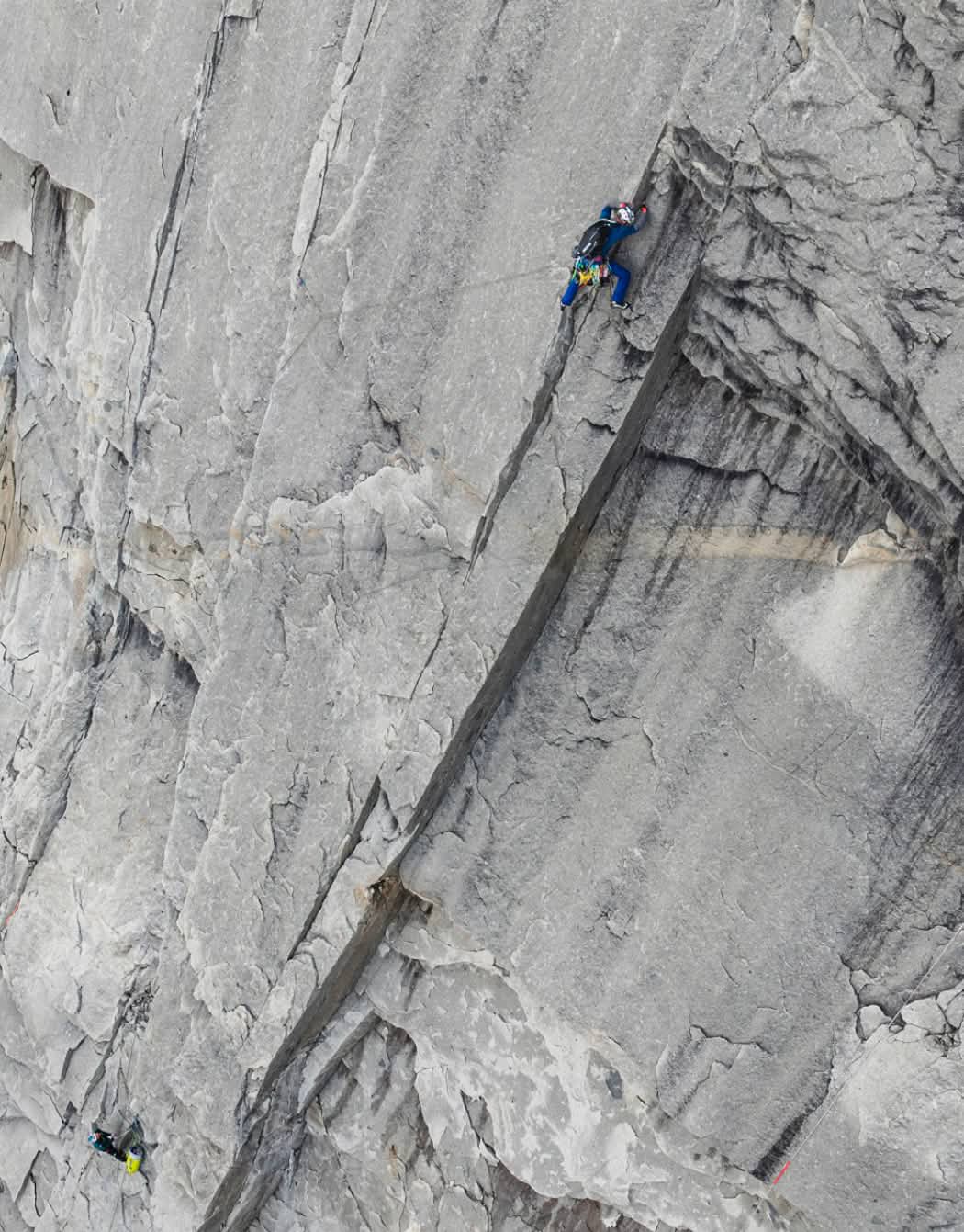A climber belays their partner on a big wall.