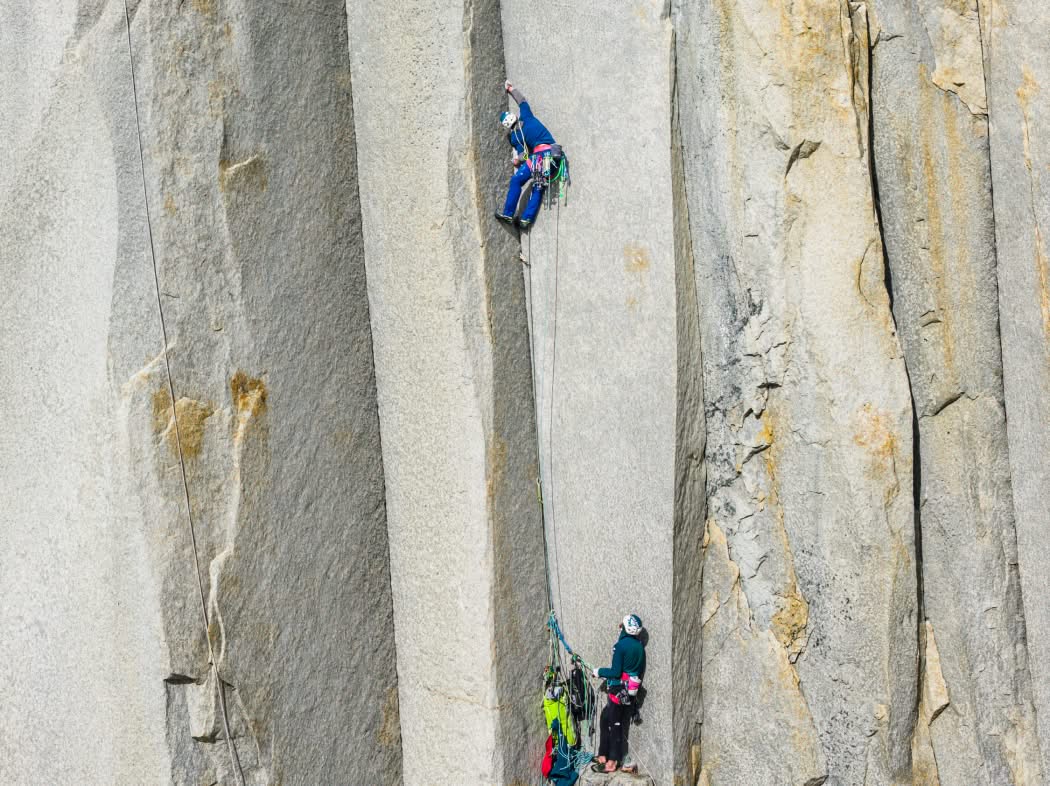A climber belays their partner on a big wall.