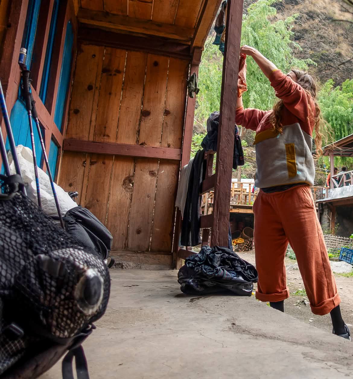 A person stands on a porch and hangs up socks on a clothesline.